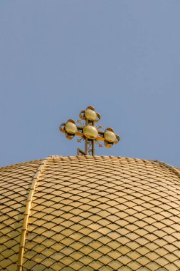 Dekoratif bir haçla kaplı altın bir Ortodoks kilise kubbesine yakın plan, açık mavi gökyüzünün altında parlıyor, inancı, ruhaniliği ve dini mirası simgeliyor..