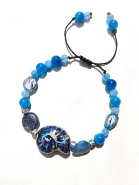 Mavi taşlar kyanit aquamarine apatite boncuklu bilezik beyaz arka planda kapalı. Güneş ışığı, yarı değerli taşların üzerindeki yanardağ. Makrame salyangoz bileziği, mücevher, aksesuar, bijouterie