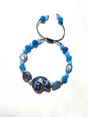 Mavi taşlar kyanit aquamarine apatite boncuklu bilezik beyaz arka planda kapalı. Güneş ışığı, yarı değerli taşların üzerindeki yanardağ. Makrame salyangoz bileziği, mücevher, aksesuar, bijouterie