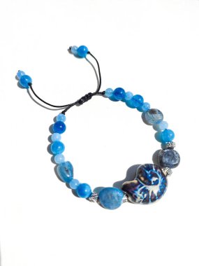Mavi taşlar kyanit aquamarine apatite boncuklu bilezik beyaz arka planda kapalı. Güneş ışığı, yarı değerli taşların üzerindeki yanardağ. Makrame salyangoz bileziği, mücevher, aksesuar, bijouterie