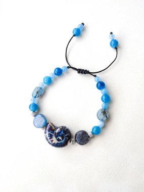 Mavi taşlar kyanit aquamarine apatite boncuklu bilezik beyaz arka planda kapalı. Güneş ışığı, yarı değerli taşların üzerindeki yanardağ. Makrame salyangoz bileziği, mücevher, aksesuar, bijouterie