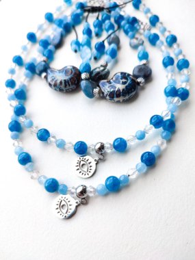 Mavi taş akuamarin apatit kyanit boncuklu mücevher düz yakın yatıyordu. Göz tılsımlı kolyeler, bilezikler. Doğal değerli taş mücevherler, aksesuarlar, moda koleksiyonu, el işleri, mücevher.