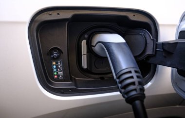 Şarj olan beyaz bir arabanın elektrik kablosunu kapat. Elektrikli araç sürdürülebilir kavramı.