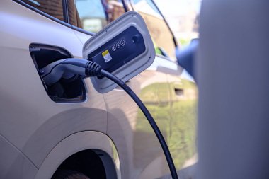Şarj olan beyaz bir arabanın elektrik kablosunu kapat. Elektrikli araç sürdürülebilir kavramı.
