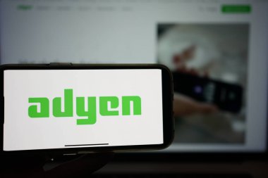 Roosendaal, Hollanda - 10 Şubat 2025: Adyen 'in logosunu gösteren bir cep telefonu, arka planda web sitesi.