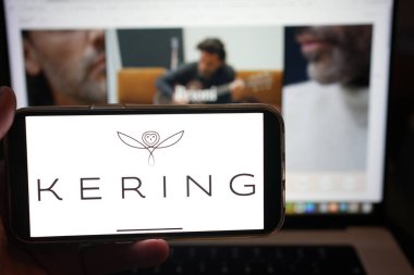 Roosendaal, The Netherlands - February 10, 2025: A mobile phone displaying the logo of Kering, with the website in the background. clipart