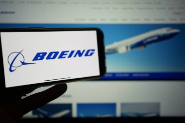 Roosendaal, Hollanda - 10 Şubat 2025: Boeing logosunu gösteren bir cep telefonu, şirketin ticari havayolu web sitesi arka planda.