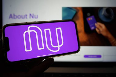 Roosendaal, Hollanda - 13 Şubat 2025: Nubank logosunu gösteren bir cep telefonu; şirketin web sitesi arka planda.