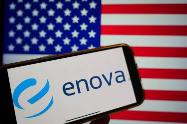Roosendaal, Hollanda - 16 Şubat 2025: Arka planda ABD bayrağı bulunan Enova Yeniliklerinin logosunu gösteren bir cep telefonu
