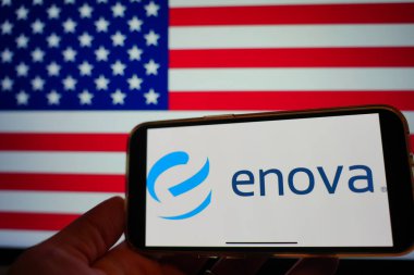 Roosendaal, Hollanda - 16 Şubat 2025: Arka planda ABD bayrağı bulunan Enova Yeniliklerinin logosunu gösteren bir cep telefonu