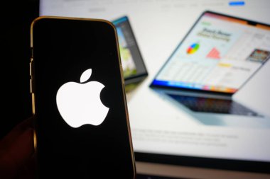 Roosendaal, Hollanda - 6 Mart 2025: Apple logosunu gösteren bir cep telefonu, arka planda M4 çipi olan yeni MacBook Air.