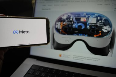 Roosendaal, Hollanda - 10 Mart 2025: Meta logosunu gösteren bir cep telefonu, arka planda Meta Quest 3S gösteriliyor.