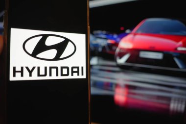 Roosendaal, Hollanda - 6 Nisan 2025: Hyundai logosunu gösteren bir cep telefonu, arka planda Ioniq 6 'nın güncellenmiş ve yüz gerdirilmiş bir resmi.