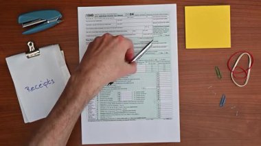 2025 vergi iadesi, 15 Nisan 1040 formu, kalemle yakın çekim. Vergi mükellefleri şaşkın, stresli, kafası karışık. Gelir vergisi, finans, evrak işleri.