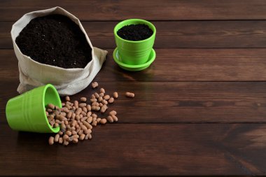 Clay Pebbles, Toprak Torbası ve Tahta Arkaplan Yeşil Tencereler ile Bahçe Malzemeleri