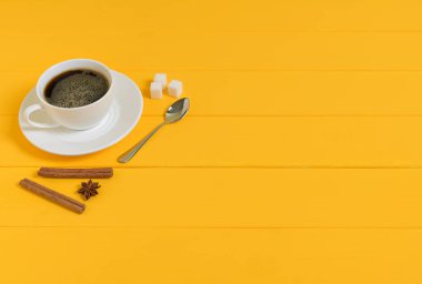 Tarçın Çubukları, Beyaz Şeker Küpleri ve Sarı Tahta Arkaplan Kaşığı olan Kahve Bardağı