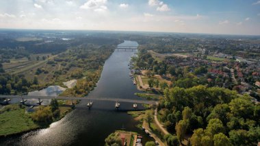 Polonya 'nın Putusk kenti ve Narew Nehri' nin havadan görünüşü. Güneşli bir sonbahar gününde köprüleri, tekneleri, ormanları ve kentsel alanları olan manzara. İHA 'dan yakalanmış.