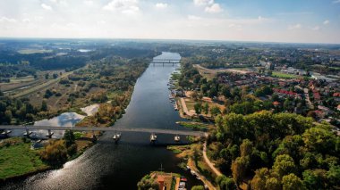 Polonya 'nın Putusk kenti ve Narew Nehri' nin havadan görünüşü. Güneşli bir sonbahar gününde köprüleri, tekneleri, ormanları ve kentsel alanları olan manzara. İHA 'dan yakalanmış.