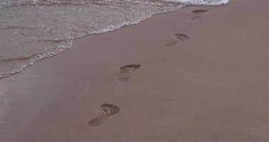 Sea wave, empty sandy shore with footprints, disappearance of footprints, slow motion
