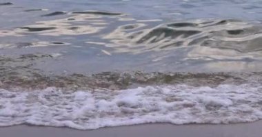 Slow motion sea wave on the sandy shore close up