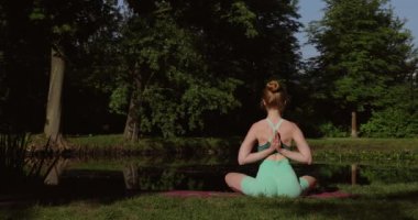Yoga sporu ve sağlıklı yaşam tarzı kavramı. Açık hava sağlık hizmetleri. Yeşil takım elbiseli kızıl saçlı atletik kız yoga yapıyor..