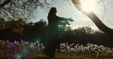 Anne ve kızı sonbahar ormanında eğleniyorlar. Bir anne kızını kollarında çevirir. Sonbaharda gün batımında mutlu insanların siluetleri.