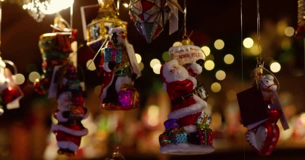Enfeites Natal Pendurados Enquanto Guirlandas Coloridas Cintilam Fundo Mercado Natal — Vídeo de Stock