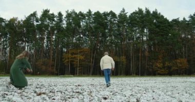 Karlı ormanda kar topu atan ve birlikte harika vakit geçiren bir çift..