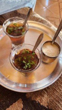 Geleneksel nane çayı bardaklarda sunulur gümüş tepside bir kase şeker küpünün yanında otantik Orta Doğu çay kültürü sergilenir..