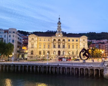 Bilbao Belediye Binası geceleri çok güzel aydınlanıyor, tarihi mimarisi ve İspanya 'nın manzaralı şehir atmosferiyle nehri yansıtıyor..