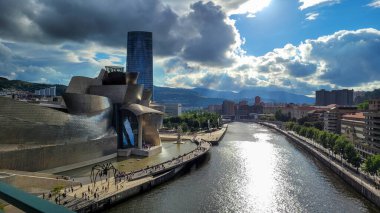 Guggenheim Müzesi 'nin muhteşem manzarası Bilbao ve Nervion Nehri' nin dramatik bir gökyüzünün altında, sudan yansıyan güneş ışığı..