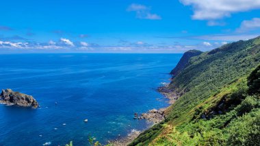 İspanya 'daki Bask kıyı şeridinin muhteşem manzarası, engebeli uçurumlar, kayalık bir ada ve parlak bir gökyüzünün altındaki derin mavi okyanus..