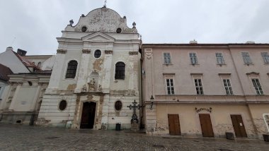 Tarihi bir Barok tarzı kilise. Yıpranmış duvarları var. Geleneksel binaların yanında Avrupa meydanında duruyor..