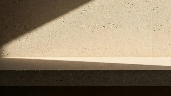 İnce, doğal dokuları olan bej taştan bir duvarın olduğu minimalist bir sahne.
