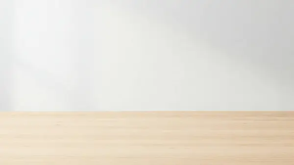 Temiz ve minimalist bir düzenek. Hafif ahşap bir masa ve düz beyaz bir duvar arka planı var.