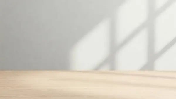 Temiz ve minimalist bir düzenek. Hafif ahşap bir masa ve düz beyaz bir duvar arka planı var.