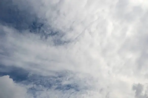 Yumuşak, ince bulutlarla dolu sakin bir gökyüzü parlak mavi bir zemin üzerinde, sakin ve huzurlu bir atmosfer yaratıyor..