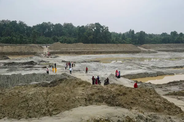 Bir grup insan su havuzlarıyla çorak ve çamurlu bir araziyi keşfediyor. Naogaon, Bangladeş 'teki kurumuş nehir..