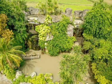 Tayland 'daki büyüleyici Rüya Dünyası eğlence parkında yoğun, yeşil ağaçların arasına yerleşmiş canlı bir su kütlesi. Bu sakin manzara doğal güzelliği ve huzurlu kaçışı vurguluyor..