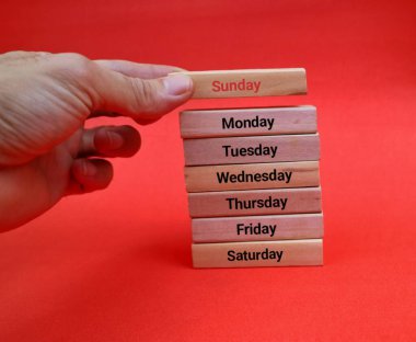 Kızıl Arkaplanda Haftanın Günlerini Gösteren Tahta Blok 'u tutan el.