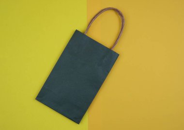 Green Paper Shopping Bag with Bright Yellow and Orange Background for Retail Theme clipart