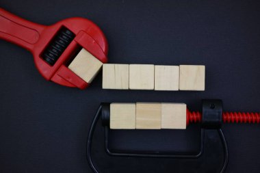 wooden blocks and wrench arranged creatively isolated on black background. free space for text