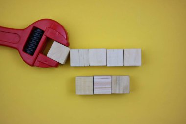 wooden blocks and wrench arranged creatively isolated on yellow background. empty space for text