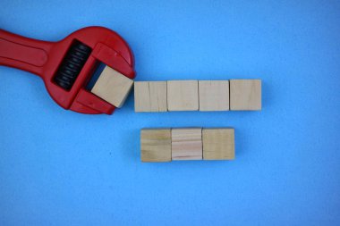 wooden blocks and wrench arranged creatively isolated on blue background. empty space for text