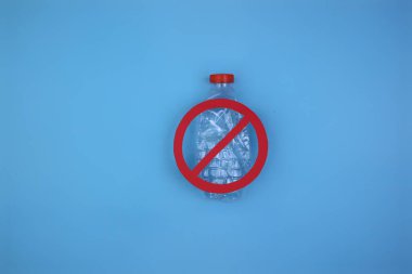 Mavi arka planda yasak işaretleri olan plastik şişeler. Plastik atık konsepti. Metin için alanı kopyala