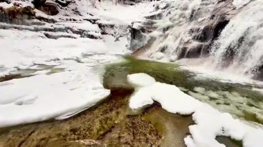 Karlı bir ormanda fırtınalı, donmuş bir şelale. Yüksek kalite 4k görüntü