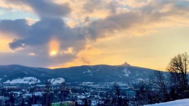 Karla kaplı dağların ve Liberec şehrinin üzerinde güzel bir günbatımı. Yüksek kalite 4k görüntü
