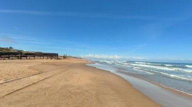 Güneşli ve güzel bir günde, nefes kesici ve pitoresk bir sahil, yumuşak altın kum ve nazik okyanus dalgaları sergiliyor.