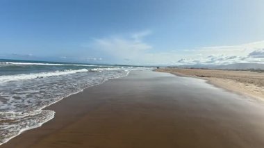 Sakin bir sahil sahnesi hayal edin yumuşak altın kumları ve parlak bir gökyüzünün altında yumuşak okyanus dalgalarını