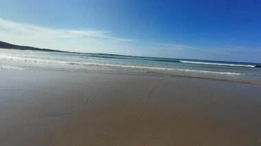 Sakin bir kumsal hayal edin, dingin dalgalar ve açık mavi bir gökyüzü, tam bir rahatlama ve gevşeme için mükemmel.